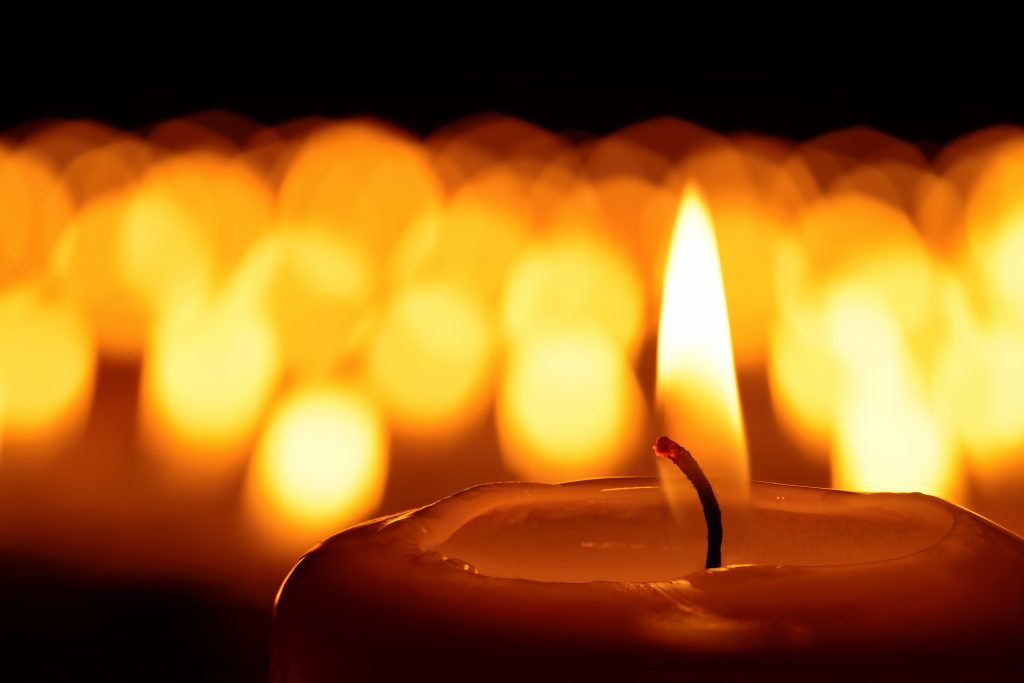 Candle in front of many defocused candleflames creating a spiritual atmosphere 